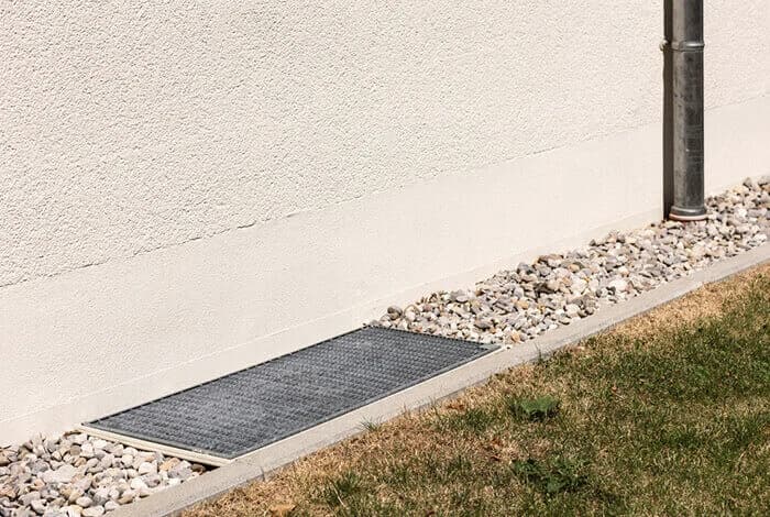 Pusset vegg med pukkstripe, rist over lysgrav og nedløp.
