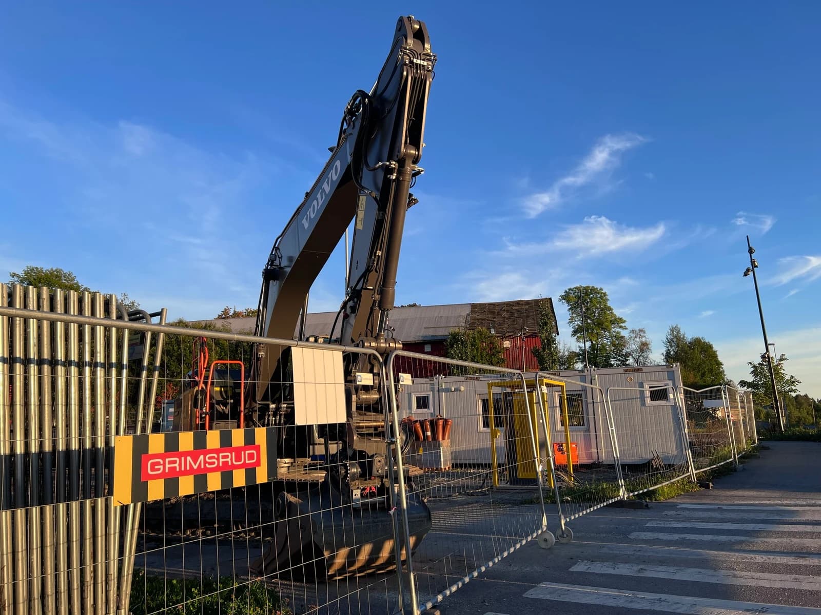 Gravemaskin og inngjerdet byggeplass ved bebyggelse i Vestby.